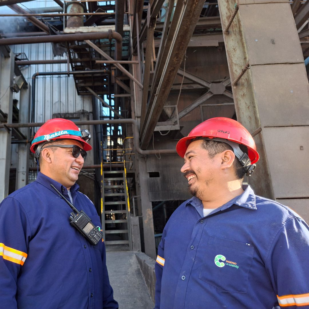 Dos colaboradores de Ingenio La Cabaña conversan y sonríen dentro de la planta